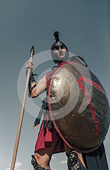 Ancient Spartan warrior in battle dress stands with shield and spear