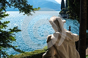 Ancient statue looks out to the lake Como from the garden of Villa Monastero, Varenna, Italy.