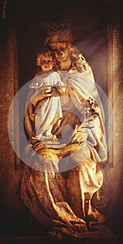 Ancient statue of Queen of Heaven Virgin Mary with Jesus Christ in sunlight. Religion, faith, love, Christianity concept