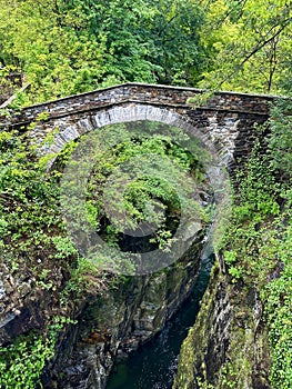 Ancient stone arch bridge over a deep gorge surrounded by lush foliage at Orrido di Sant\'Anna, Traffiume, Cannobio, Piemont