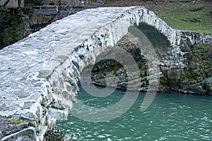 Ancient stone arched Makhuntseti, Qween Tamars Bridge, over mountain river Acharistskali , cloudy day , travek Georgia photo