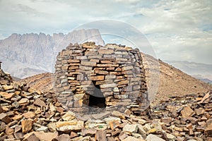 Ancient stone beehive tombs with Jebel Misht mountain in the background, archaeological site near al-Ayn, sultanate Oman photo