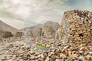 Ancient stone beehive tombs with Jebel Misht mountain in the background, archaeological site near al-Ayn, sultanate Oman photo