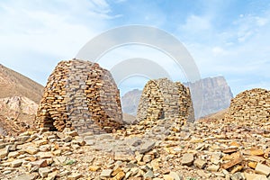 Ancient stone beehive tombs with Jebel Misht mountain in the background, archaeological site near al-Ayn, sultanate Oman photo