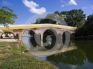 Ancient stone bridge crossing a river, reflection of the bridge in the green river, medieval rural town photo