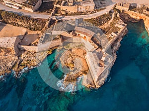 Ancient stone military fort Malta island made of brick rocks on shore blue sea with view city Valetta, aerial top view