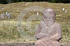 Ancient stone sculpture of a man and other carvings on the background near the Burana Tower