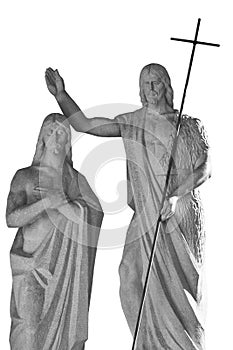 Ancient stone statue of John the Baptist baptizing Jesus Christ. Black and white statue isolated on white background