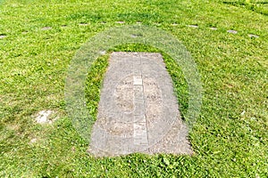 Ancient stone sundial among the green grass, outdoor, close up