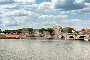 Ancient stone Tiberius bridge and old town buildings cityscape in Rimini