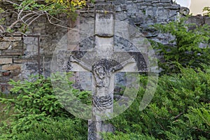 Ancient stone tombstone in form of crucified Jesus on cemetery