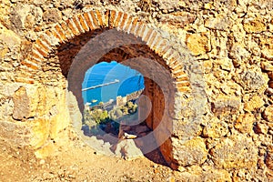 Ancient stone wall of Alanya Castle, view of the bay through the arch