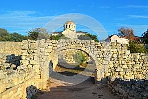 Ancient stone wall and arch in Chersonesos with a view of St. Vladimir's Cathedral under the blue sky