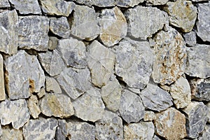 Ancient stone wall of the fortress. Masonry of old yellow stones and bricks. Unusual background.