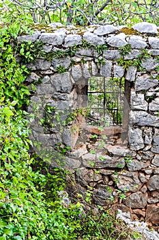 An ancient stone wall of a ruined house with a window among the grass. Old house, ruins, background