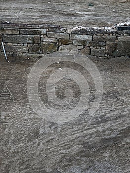 Ancient stone wall under reconstruction with rocks methodically stacked in sandy soil