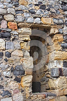 Ancient stone wall with window without glass. Medieval architecture concept. Antique stonework. Old castle wall.