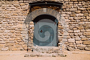 Ancient stonewall with black door. Antique building exterior of fortes