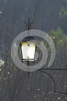 Ancient street lamp lit at dusk