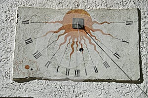 Ancient sundial with signs of the zodiac on white wall