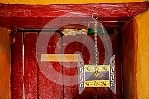 Ancient Tibetan incense tools in Buddhist temple against red wood door