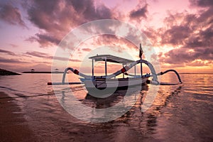 Ancient traditional Janggolan fishing boat on seashore at colorful sunrise