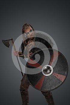 Ancient viking with shield and black fur against gray background