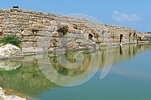 Ancient wall reflecting in the pond in Nahal Taninim archeological park, Israel