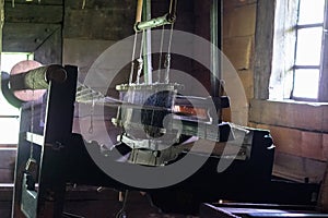 The ancient weaving loom in an interior of a wooden log hut.