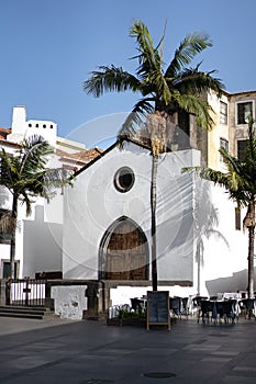 Ancient white church under the sun, palm trees in the street
