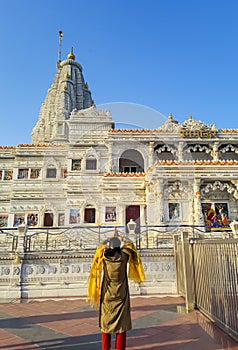ancient white marble architecture with devotee offering salutation at dusk from flat angle
