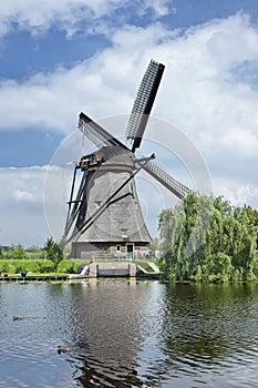 Ancient wind mill reflected in a blue canal on a summer day
