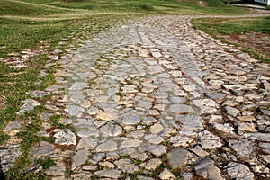 Ancient winding road paved with cobblestone .