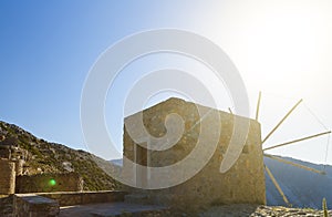 Ancient windmills against a bright blue sky and sun with rays of Lasithi Plateau on Crete, Greece