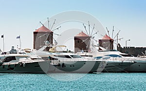 Ancient windmills and yachts in port of Rhodes town on Rhodes island, Greece