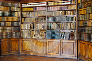 Ancient wooden book shelves with old library books Dusty bookshelf with rare books collection in bookcase Retro library photo