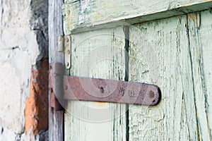 Ancient wooden door background. Fragment of old gate with remnants of green paint and rusty hinges