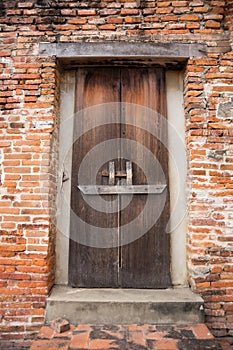 Ancient wooden door on brick wall