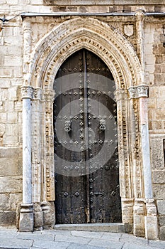 Ancient wooden door of the Cathedral of Toledo (Primate Cathedral of Saint Mary) with carved stone frame