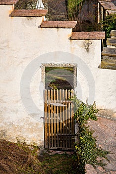 Ancient wooden door with lattice in white stone wall