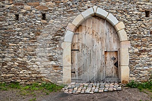 Ancient wooden door in old stone castle wall.