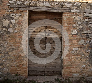 Ancient wooden door in old stones brick wall