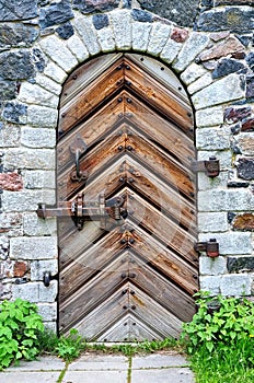 Ancient wooden door in a stone wall of a fortification construction