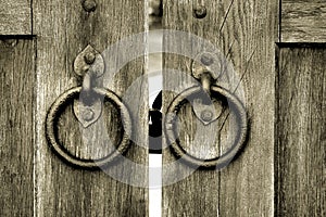 Ancient wooden gate with door knocker rings