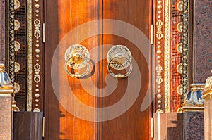 Ancient wooden gate with two golden door knocker rings close-up front view. Old Door Fragment of Buddhist temple Datsan