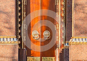 Ancient wooden gate with two golden door knocker rings close-up front view. Old Door Fragment of Buddhist temple Datsan