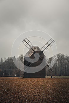 Ancient wooden mill standing alone in a field in gloomy foggy weather. Historical building for grinding corn, Opava, Czech