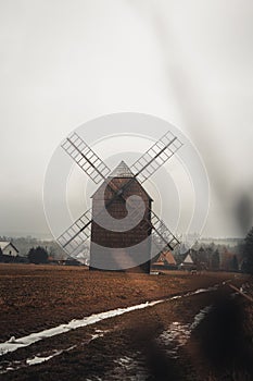 Ancient wooden mill standing alone in a field in gloomy foggy weather. Historical building for grinding corn, Opava, Czech