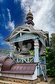 An ancient wooden Orthodox church with a cross on the dome and large bells.
