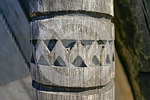 An ancient wooden pillar with a carved pattern.